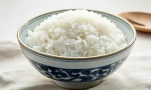 Una ciotola di riso bianco fumante, ideale come riso per diabetici, su un tessuto grezzo.