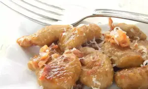 Gnocchi e lenticchie dorati, conditi con formaggio grattugiato e un tocco di pancetta croccante.