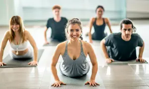 Gruppo di persone che praticano pilates posturale in una luminosa palestra, concentrati e sorridenti.