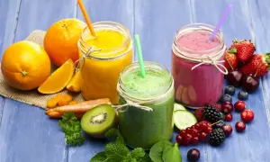 Tre smoothie colorati, uno arancione, uno verde e uno rosa, con frutta fresca e verdura. Ideali come smoothie per dimagrire.