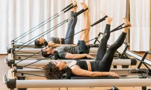 Persone in posa sul pilates reformer, scopri cos'è questo attrezzo per un allenamento completo.