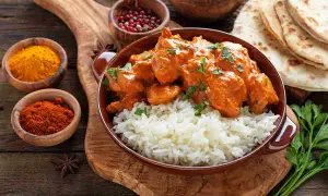 Un saporito curry con riso basmati, accompagnato da spezie e pane naan. I condimenti creano un piatto invitante.