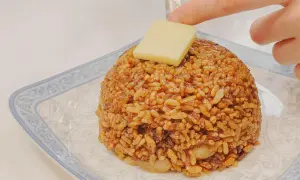 Un monticello di riso con salsa di soia e uova, guarnito con un cubetto di formaggio.