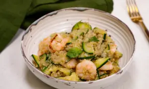 Un piatto colorato con zucchine e legumi, gamberetti e basilico fresco. Un pasto leggero e nutriente.