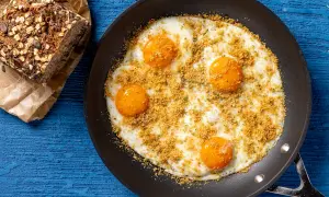 Uova fritte in padella con pangrattato e erbe, accompagnate da pane integrale. Un'idea per ricette fit con uova, sana e gustosa.