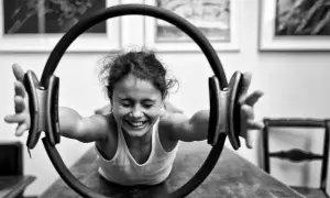 Bambina sorridente si allena con un cerchio pilates, mostrando la gioia degli esercizi.