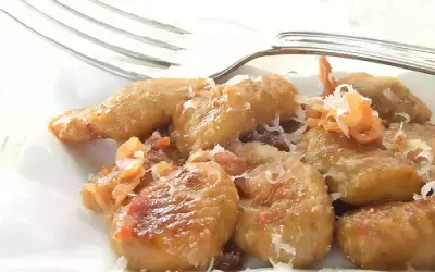 Gnocchi e lenticchie dorati, conditi con formaggio grattugiato e un tocco di pancetta croccante.
