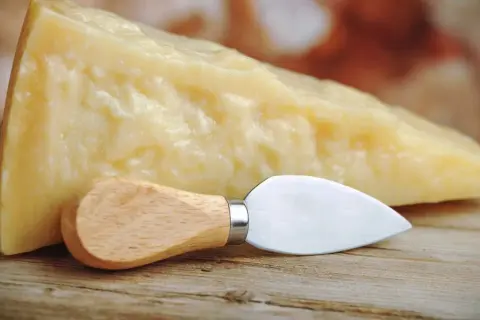 Un pezzo di Grana Padano, naturalmente privo di lattosio, pronto per essere gustato con il suo coltellino.