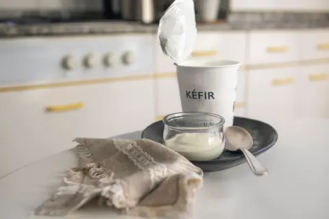 Kefir in un vasetto, pronto per una colazione chetogenica. Un cucchiaino e un tovagliolo completano la scena.