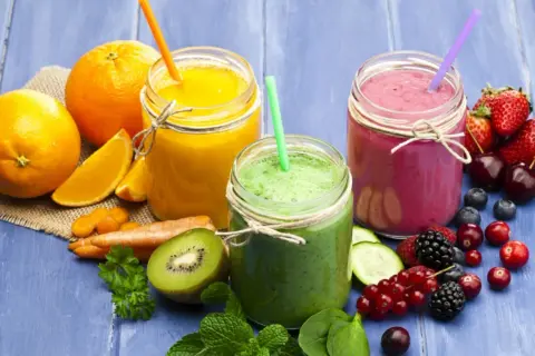 Tre smoothie colorati, uno arancione, uno verde e uno rosa, con frutta fresca e verdura. Ideali come smoothie per dimagrire.