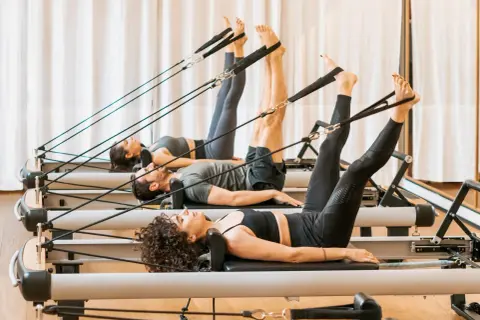 Persone in posa sul pilates reformer, scopri cos'è questo attrezzo per un allenamento completo.