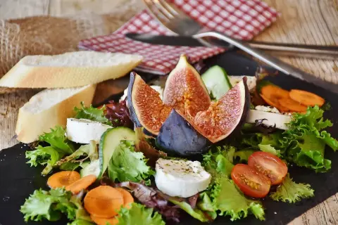 Insalata fresca con fichi, formaggio di capra e pane. Un'opzione leggera per chi soffre di colon irritabile, evitando gli spinaci.