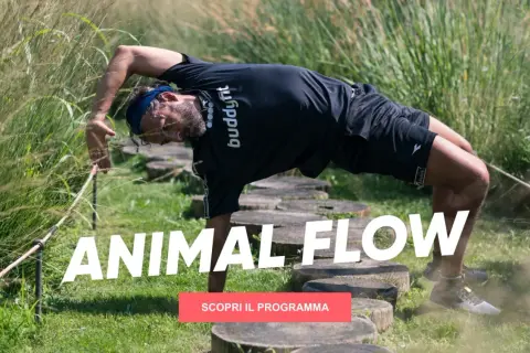 Uomo in posizione di animal flow, con il corpo arcuato e una mano a terra, immerso nella natura.