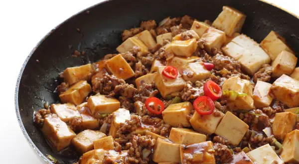 Tofu e lenticchie in padella, un piatto saporito con cubetti di tofu, carne macinata e peperoncino.