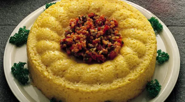 Sformatini di riso e verdure dorati, guarniti con un trito colorato e prezzemolo fresco.
