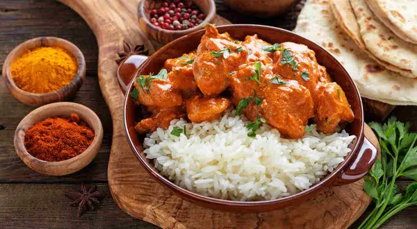Un saporito curry con riso basmati, accompagnato da spezie e pane naan. I condimenti creano un piatto invitante.