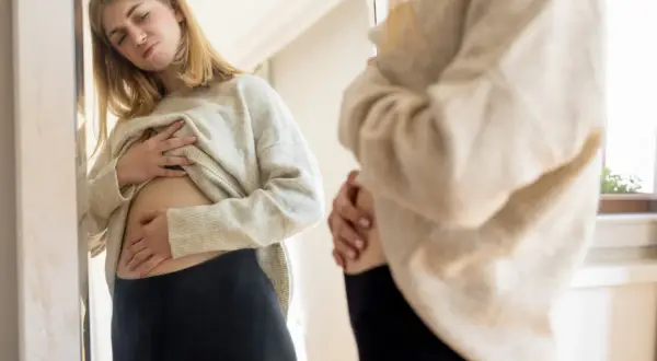 Ragazza preoccupata si tocca la pancia, forse il latte di riso gonfia la pancia.