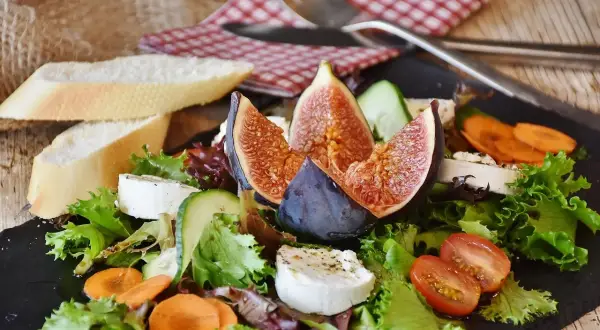 Insalata fresca con fichi, formaggio di capra e pane. Un'opzione leggera per chi soffre di colon irritabile, evitando gli spinaci.