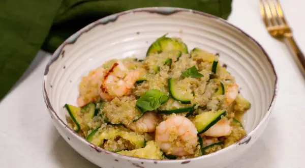 Un piatto colorato con zucchine e legumi, gamberetti e basilico fresco. Un pasto leggero e nutriente.