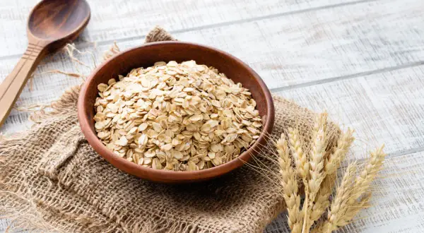 Ciotola di avena integrale, ricca di fibre e nutrienti, pronta per una colazione sana. Le sue proprietà la rendono un alimento ideale per il benessere.