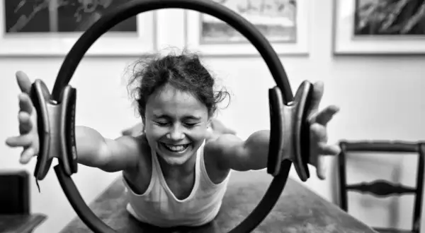 Bambina sorridente si allena con un cerchio pilates, mostrando la gioia degli esercizi.