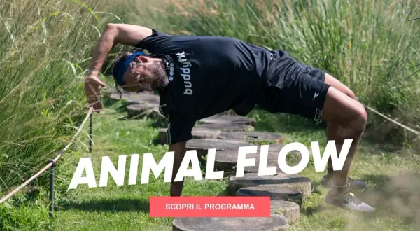 Uomo in posizione di animal flow, con il corpo arcuato e una mano a terra, immerso nella natura.