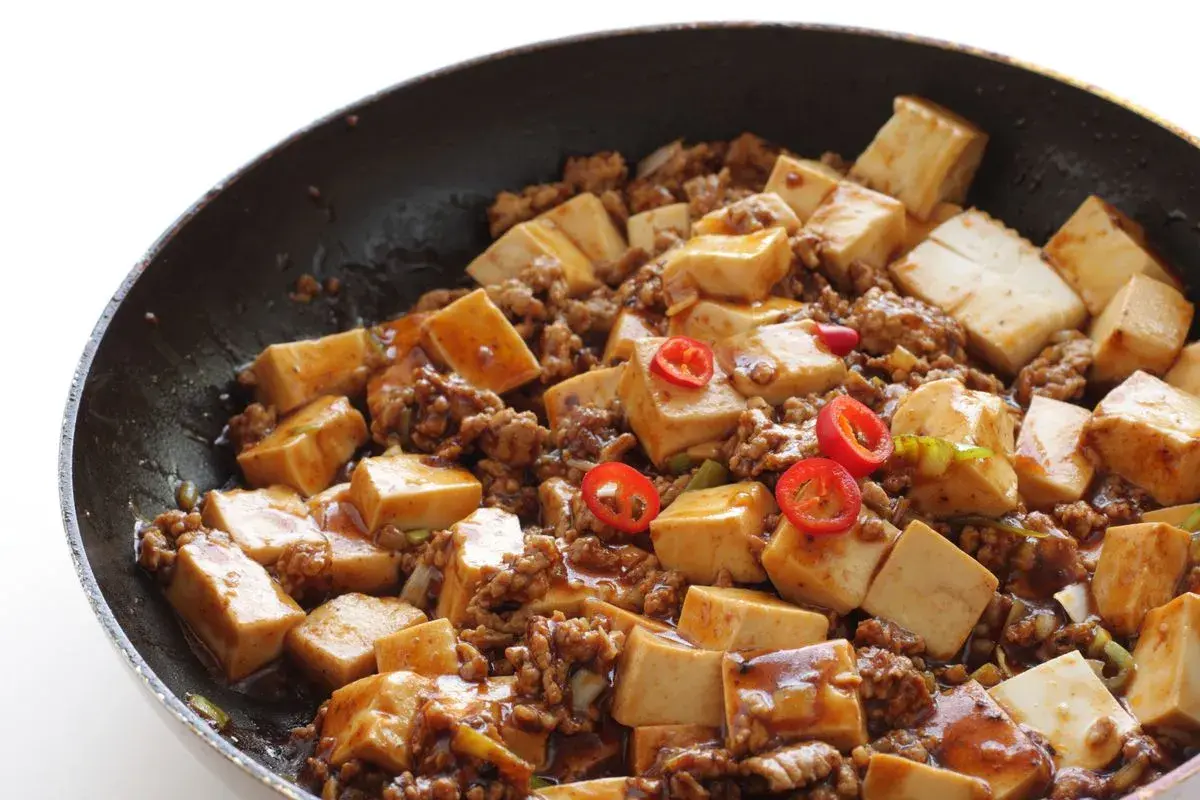 Tofu e lenticchie in padella, un piatto saporito con cubetti di tofu, carne macinata e peperoncino.