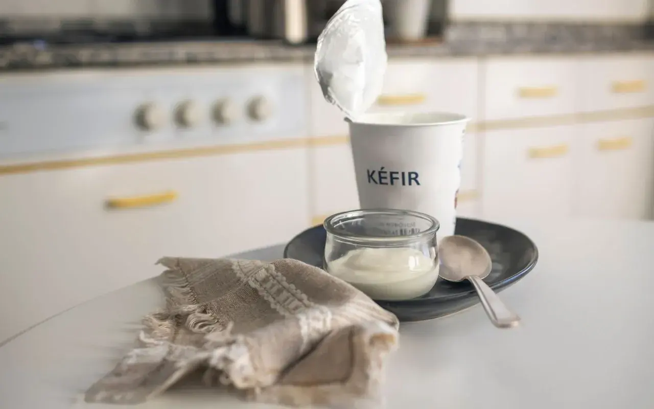Kefir in un vasetto, pronto per una colazione chetogenica. Un cucchiaino e un tovagliolo completano la scena.