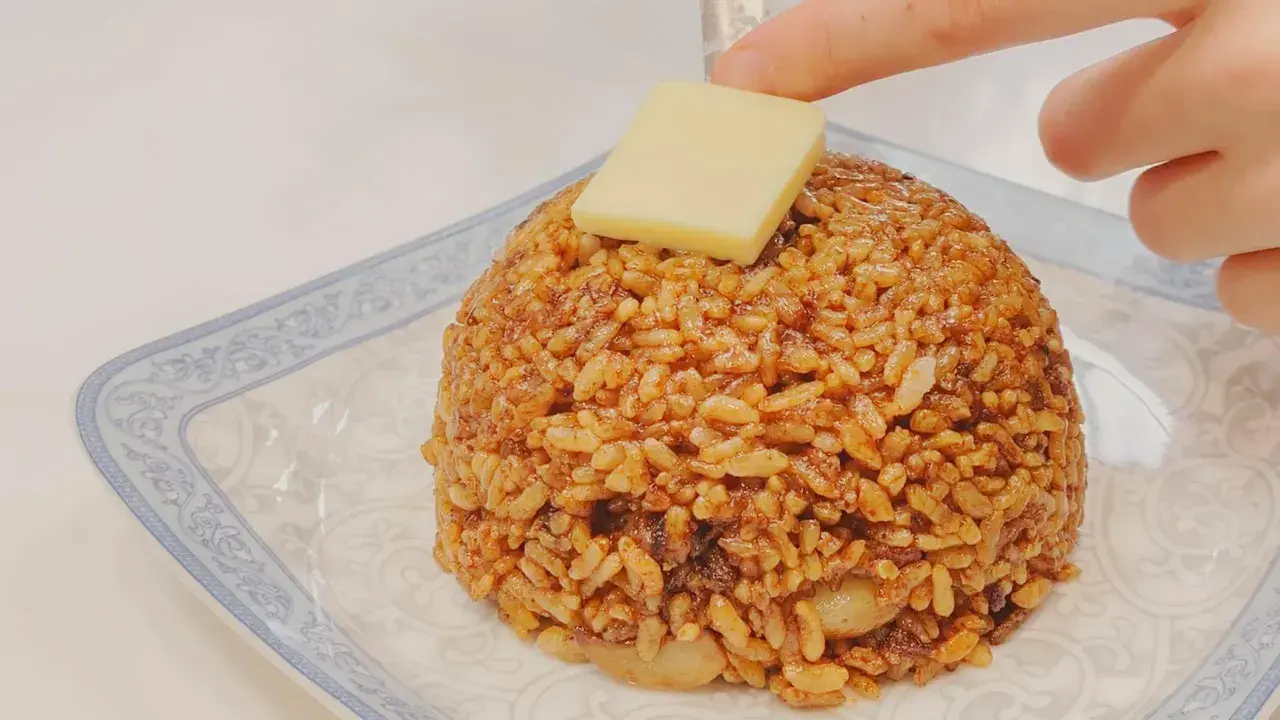 Un monticello di riso con salsa di soia e uova, guarnito con un cubetto di formaggio.