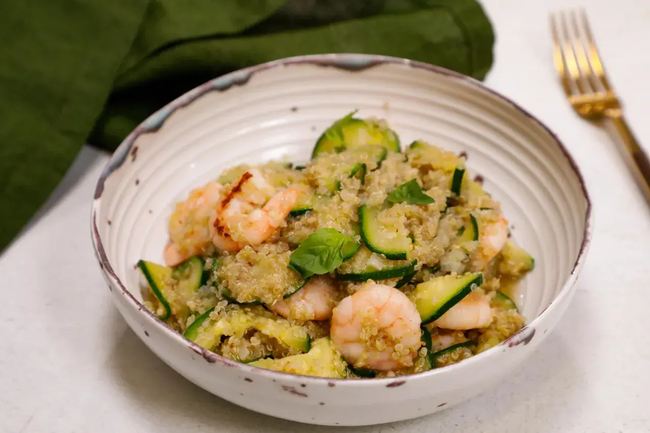 Un piatto colorato con zucchine e legumi, gamberetti e basilico fresco. Un pasto leggero e nutriente.