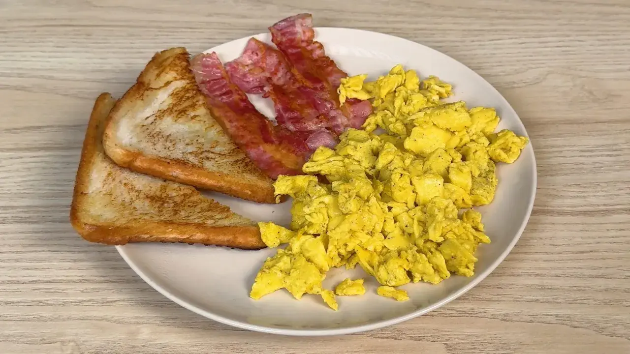 Piatto con uova strapazzate, bacon croccante e pane tostato. Un classico per iniziare la giornata con gusto.