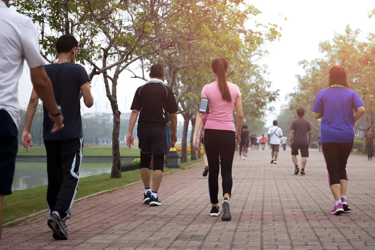 Persone che fanno una camminata metabolica in un parco, godendosi l'aria aperta e il movimento.