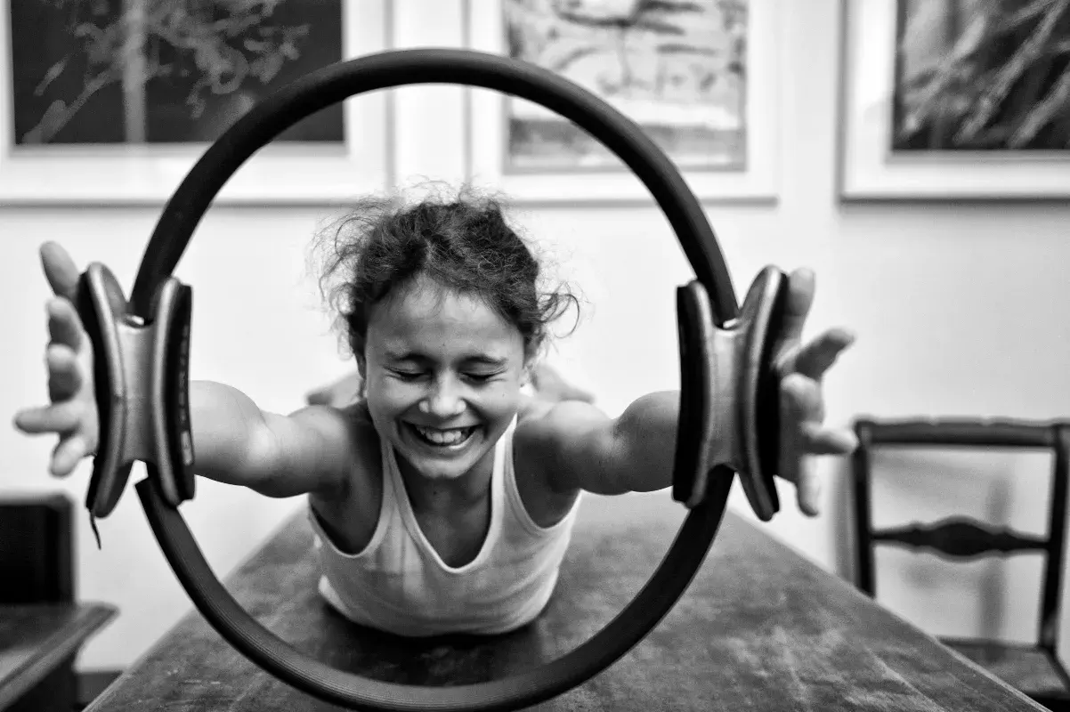 Bambina sorridente si allena con un cerchio pilates, mostrando la gioia degli esercizi.