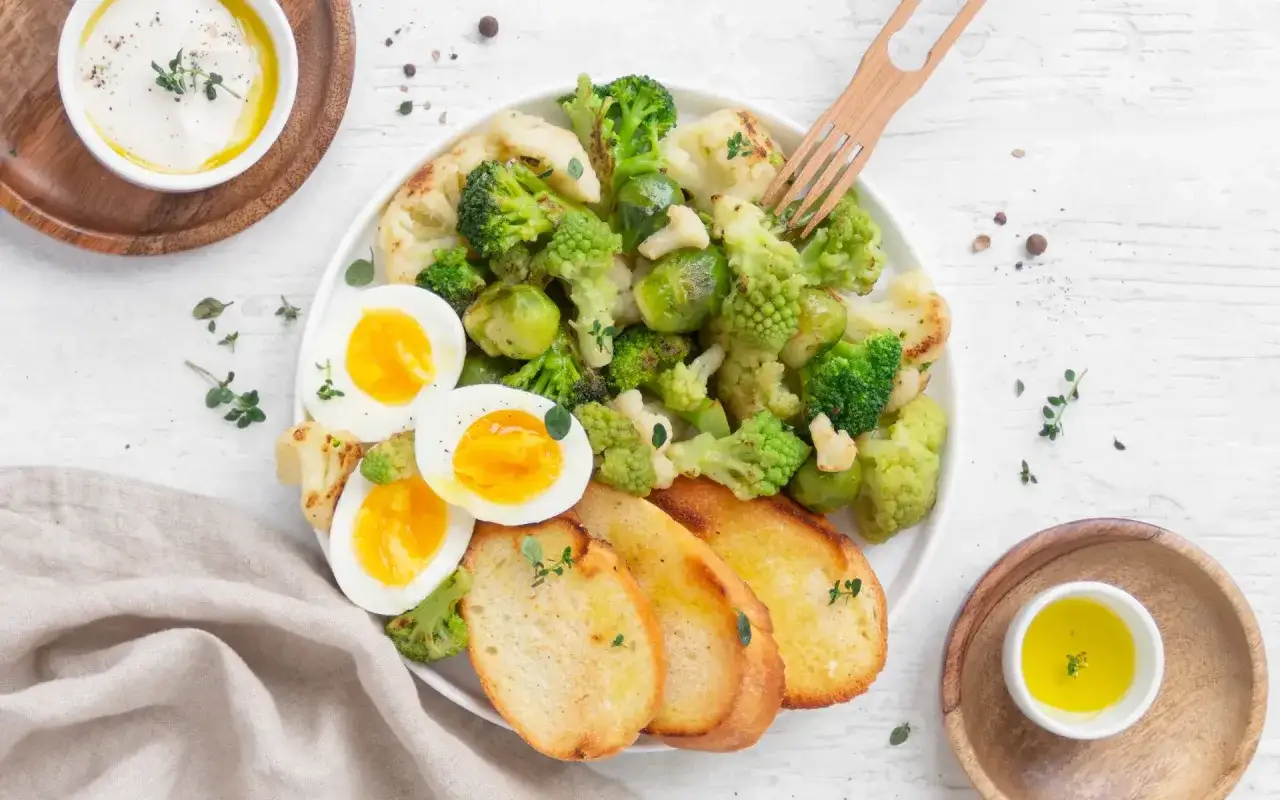Piatto con uova sode, verdure miste (broccoli, cavolfiore, cavolini di Bruxelles) e crostini. Un'idea per un pasto leggero e gustoso.
