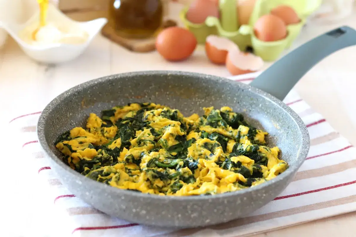 Uova strapazzate con spinaci in padella, un'idea gustosa su cosa abbinare alle uova strapazzate per un pasto completo.
