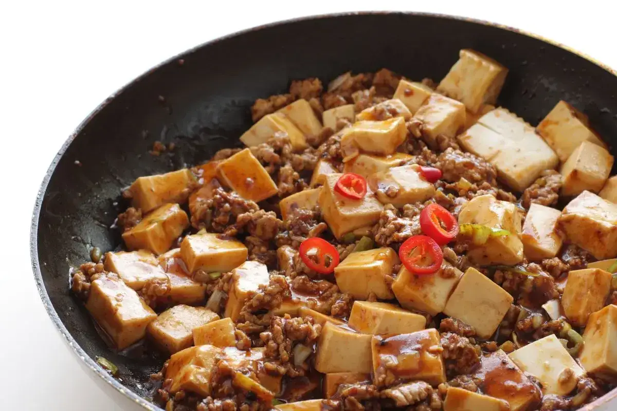 Tofu e lenticchie in padella, un piatto saporito con cubetti di tofu, carne macinata e peperoncino.
