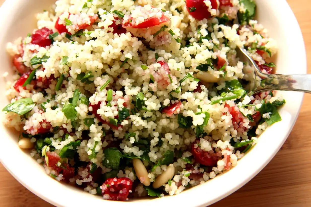Insalata di cous cous con pomodorini, prezzemolo e pinoli. Un piatto leggero e gustoso, ideale per chi cerca un'alternativa sana al colesterolo.