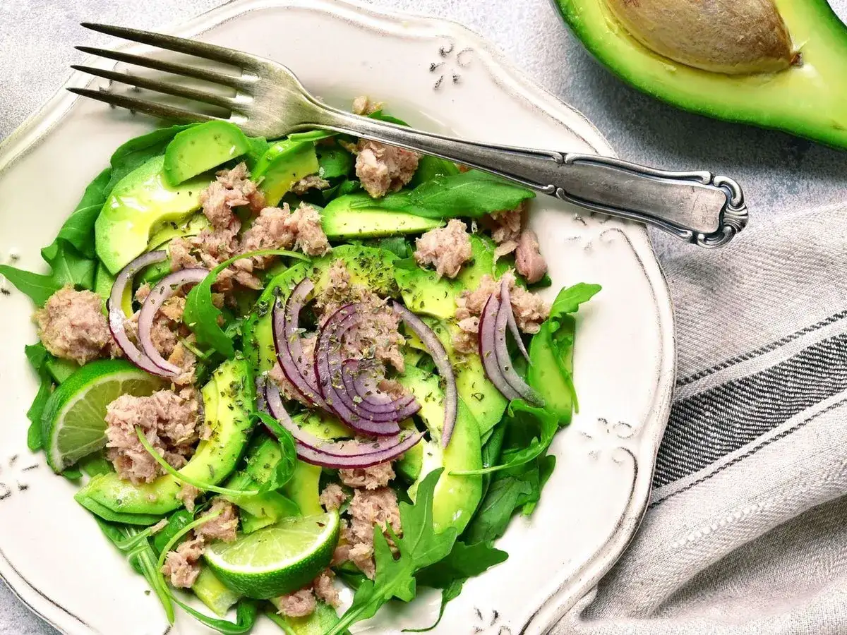 Insalata fresca con avocado, tonno, cipolla rossa e lime. Un piatto gustoso che dimostra come l'avocado fa dimagrire, saziando e nutrendo.