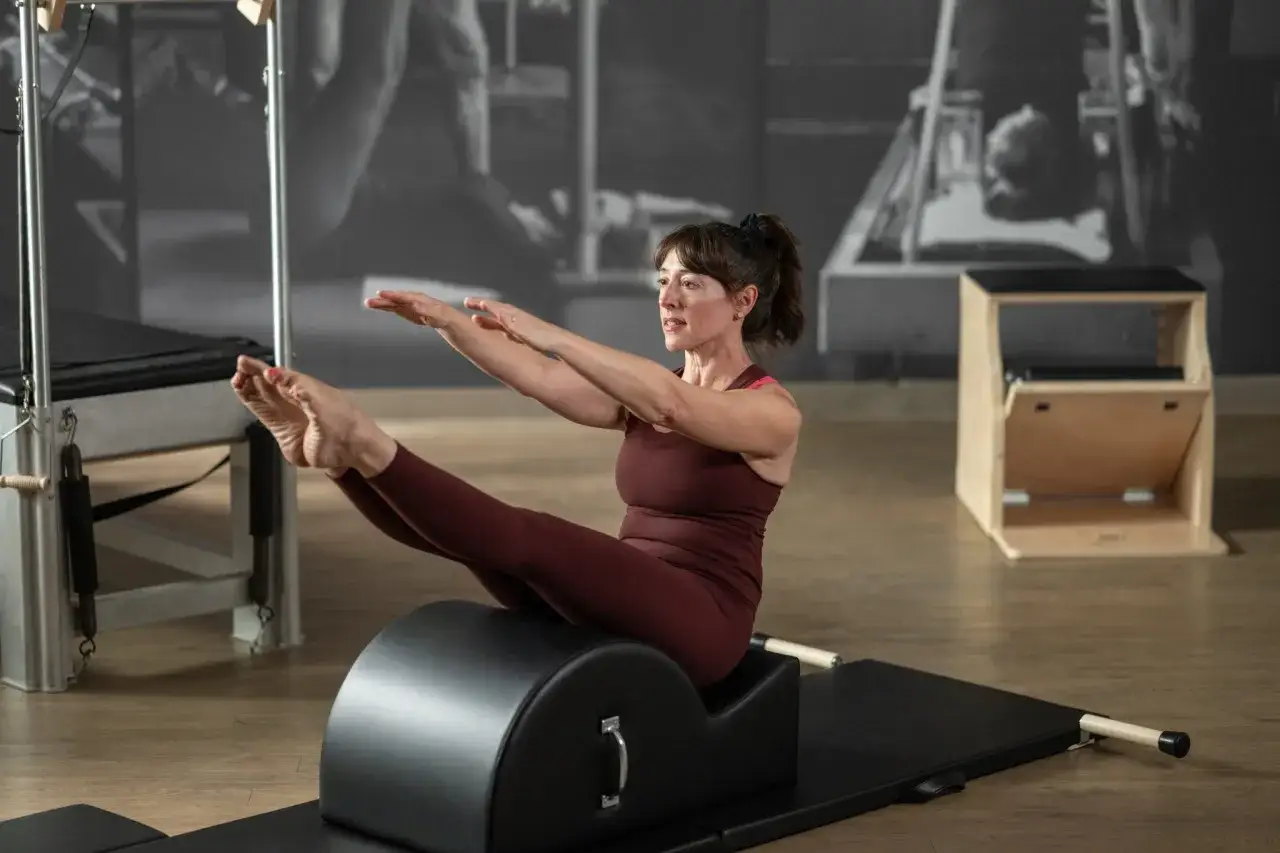 Donna esegue esercizi pilates sul reformer, concentrata e con le gambe sollevate.