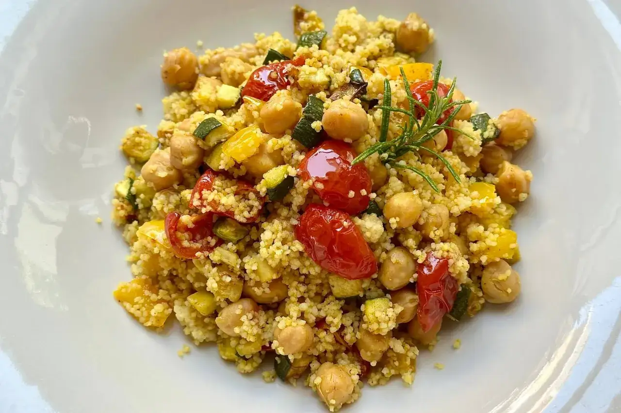 Couscous con ceci, zucchine e pomodorini, un piatto che evoca le sue origini mediterranee.