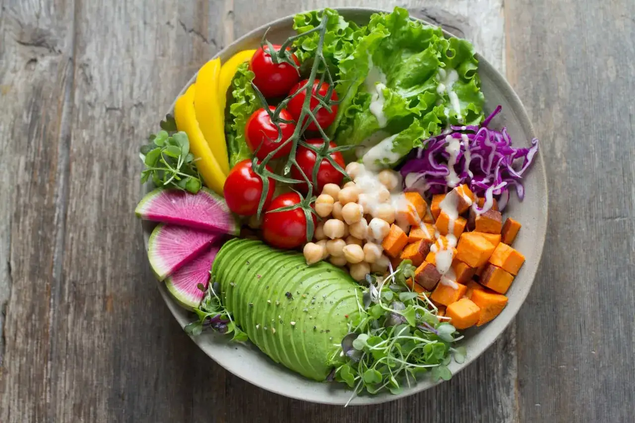 Piatto colorato con avocado, ceci, patate dolci, pomodorini, peperoni gialli, cavolo rosso e germogli. Ideale per una dieta vegetariana per perdere 5 kg in una settimana.