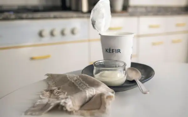 Kefir in un vasetto, pronto per una colazione chetogenica. Un cucchiaino e un tovagliolo completano la scena.