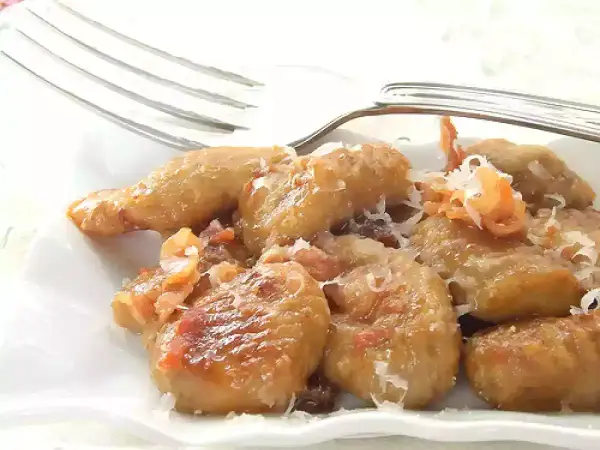 Gnocchi e lenticchie dorati, conditi con formaggio grattugiato e un tocco di pancetta croccante.