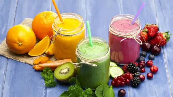 Tre smoothie colorati, uno arancione, uno verde e uno rosa, con frutta fresca e verdura. Ideali come smoothie per dimagrire.