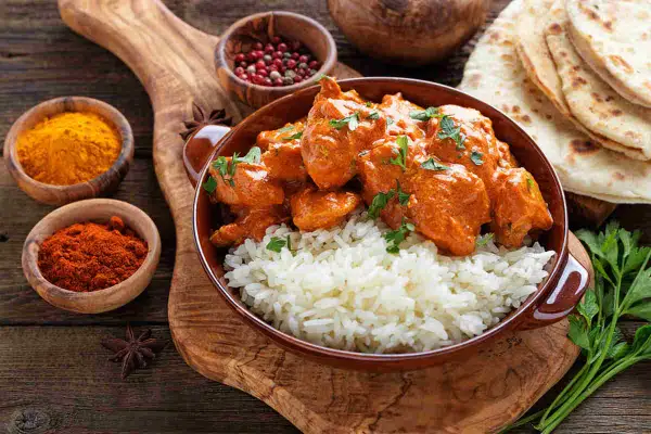 Un saporito curry con riso basmati, accompagnato da spezie e pane naan. I condimenti creano un piatto invitante.