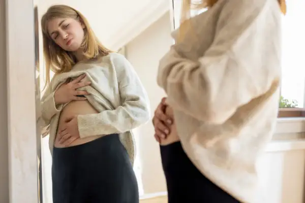 Ragazza preoccupata si tocca la pancia, forse il latte di riso gonfia la pancia.