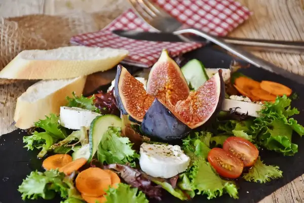 Insalata fresca con fichi, formaggio di capra e pane. Un'opzione leggera per chi soffre di colon irritabile, evitando gli spinaci.