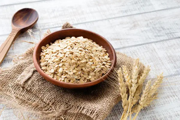 Ciotola di avena integrale, ricca di fibre e nutrienti, pronta per una colazione sana. Le sue proprietà la rendono un alimento ideale per il benessere.
