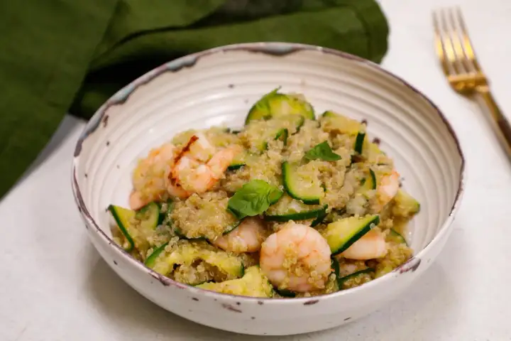 Un piatto colorato con zucchine e legumi, gamberetti e basilico fresco. Un pasto leggero e nutriente.